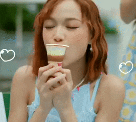 a woman in a blue dress is eating a cup of ice cream .