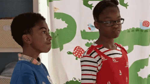 a boy and a girl are standing next to each other in front of a shower curtain with animals on it .