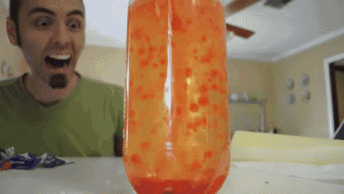 a man in a green shirt is looking at a bottle of lava