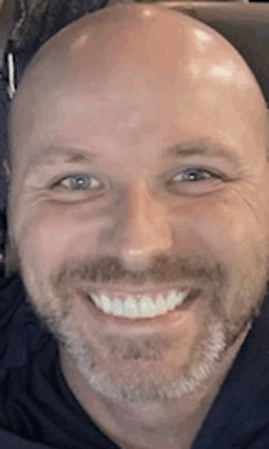 a man with a beard is smiling for the camera .