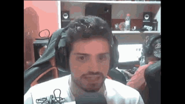 a man with a beard is wearing headphones and a microphone while sitting in front of a computer .