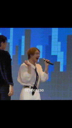 a man is singing into a microphone while standing next to another man on a stage .