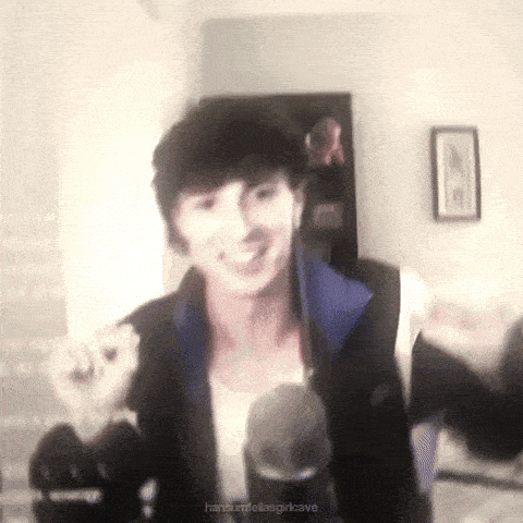 a young man is standing in front of a microphone in a living room .