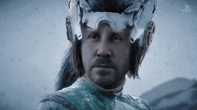 a man with a beard and a helmet on his head is standing in the snow .
