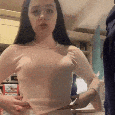 a woman is standing in a kitchen wearing a pink top