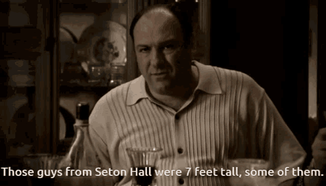 a man sitting at a table with the words " those guys from seton hall were 7 feet tall some of them " next to him