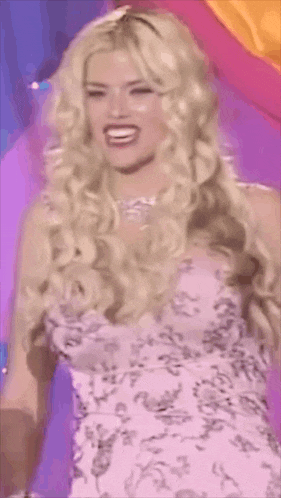 a woman with blonde hair and a pink dress is smiling