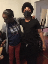 a man wearing a mask is standing next to a woman in a blue shirt