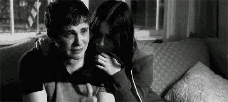 a man and a woman are sitting on a couch . the woman is comforting the man who is crying .