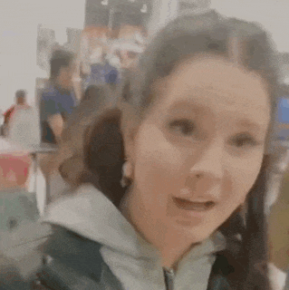 a woman is making a funny face in a blurry photo while standing in a crowded room .
