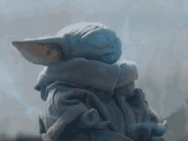 a baby yoda from star wars is sleeping with his eyes closed .