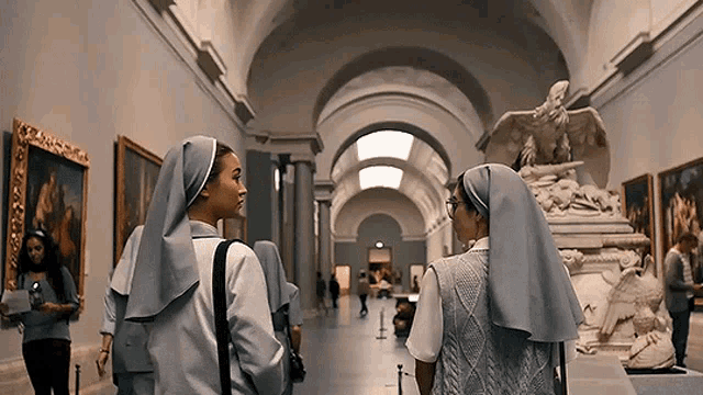 two nuns are standing in a museum looking at paintings