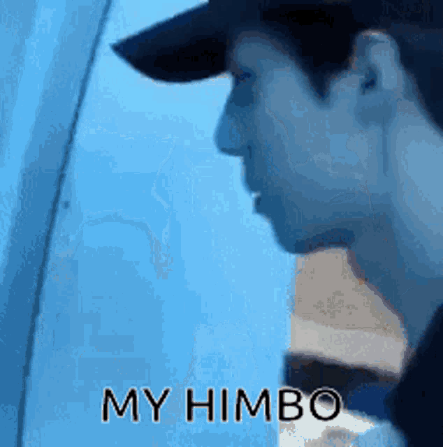 a man wearing a baseball cap is looking out a window with the words my himbo written below him