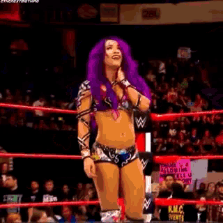 a wrestler with purple hair is standing in a wrestling ring .