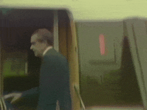 a man in a suit is walking out of an airplane door