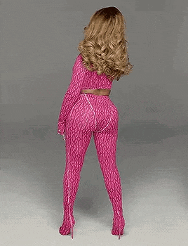 a woman wearing a pink jumpsuit and sunglasses is standing on a white surface .