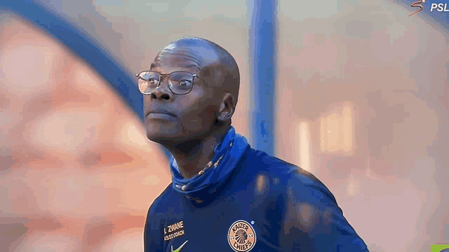 a man wearing glasses and a blue shirt that says ridge chiefs on it