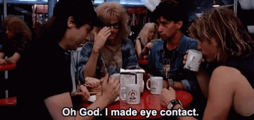 a group of people are sitting at a table in a restaurant talking to each other .