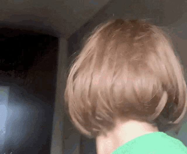 a close up of a person 's head with short hair and a green shirt