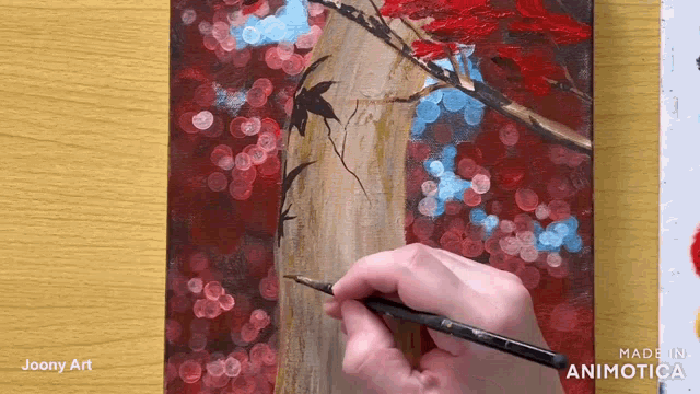 a person is painting a tree with a brush on a wooden table .