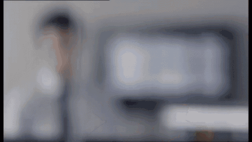 a blurry picture of a person standing next to a computer monitor