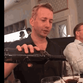 a man is pouring wine into a glass at a restaurant