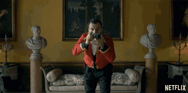 a man in a red jacket is taking a picture with a netflix logo in the background