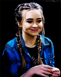 a girl with braids is smiling and wearing a blue shirt