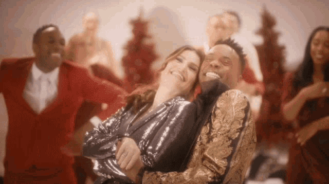 a man and a woman are hugging and laughing in front of a group of people