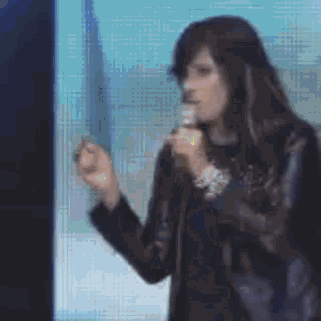 a woman in a black jacket is holding a microphone and giving a presentation .