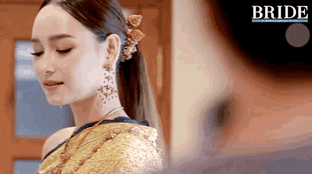 a woman in a gold dress is standing in front of a bride ad