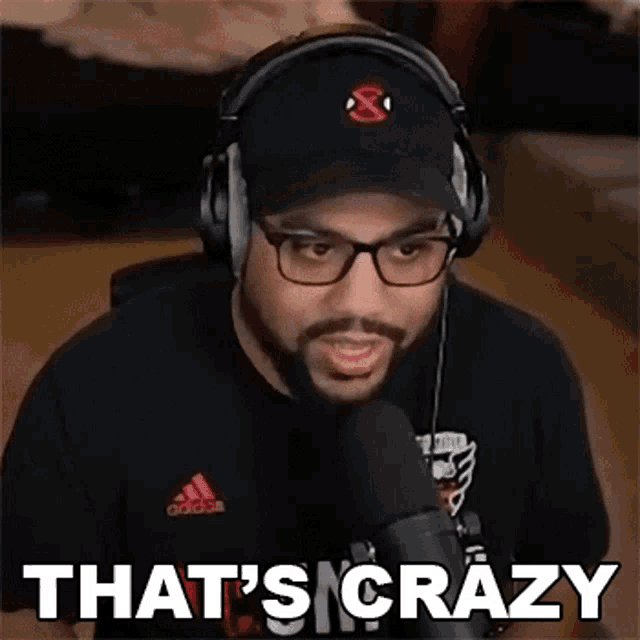 a man wearing headphones and a hat is talking into a microphone and says that 's crazy .