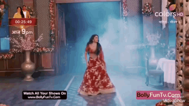 a woman in a red dress is dancing in front of a sign that says bolly funtv.com