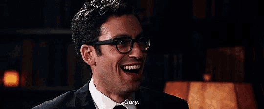 a man wearing glasses and a suit is smiling and talking to another man .