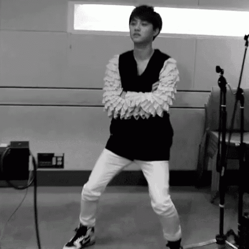 a black and white photo of a young man standing on one leg