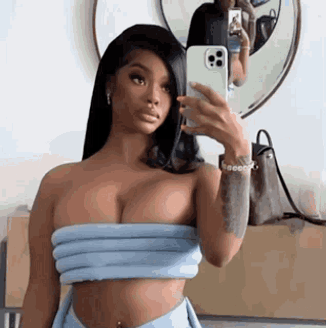 a woman is taking a selfie in front of a mirror with her cell phone .