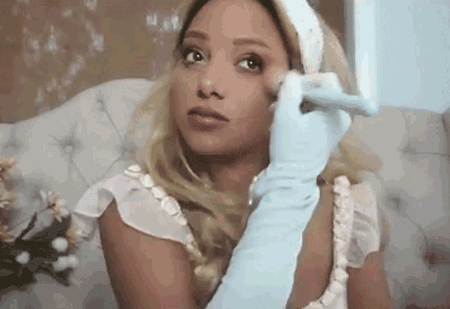 a woman is sitting on a couch applying makeup to her face .