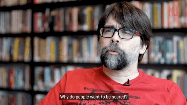 a man wearing glasses and a red shirt is asking why do people want to be scared