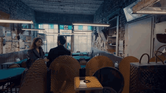 a man and a woman sit at a table in a restaurant with a sign that says ' pizza ' on it