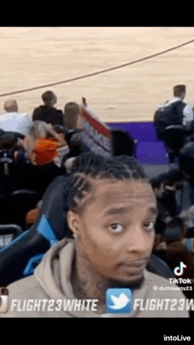 a man is sitting in a basketball stadium watching a game .