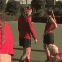 a group of girls are standing on a field and one of them is kneeling down
