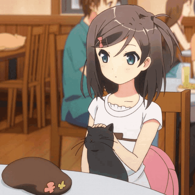 a girl sitting at a table with a black cat