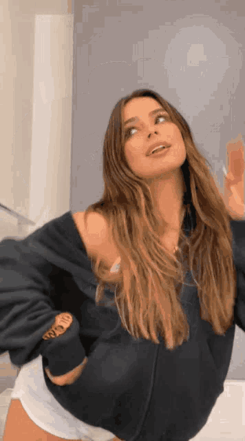 a woman with long hair is wearing a black hoodie and white shorts