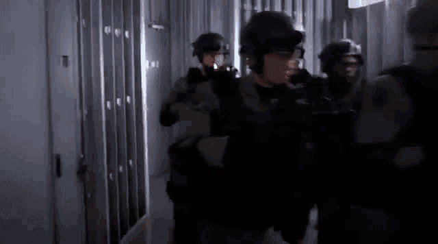 a group of soldiers are walking down a hallway with lockers .