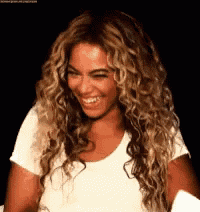 a woman with curly hair is smiling and wearing a white shirt .