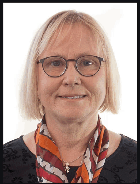 a woman wearing glasses and a scarf looks at the camera