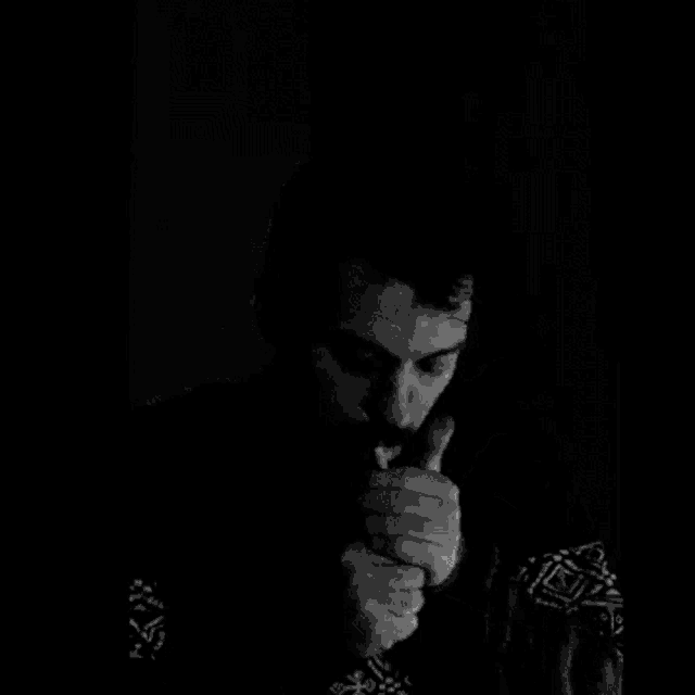 a man with a mustache is smoking a cigarette in the dark .