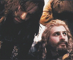 a man with a beard is holding a dog and says " kili kili "