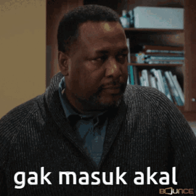 a man in a grey sweater has the words " gak masuk akal " on his face