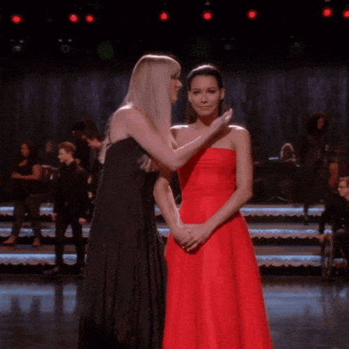 a woman in a red dress touches another woman 's face